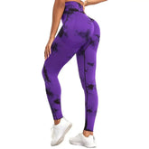 Woman wearing purple and black seamless tie dye ankle-length yoga pants with elastic waistband and white sneakers