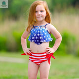 Girl wearing a girls patriotic 2 piece red white and blue stars and stripes tankini swimsuit outdoors