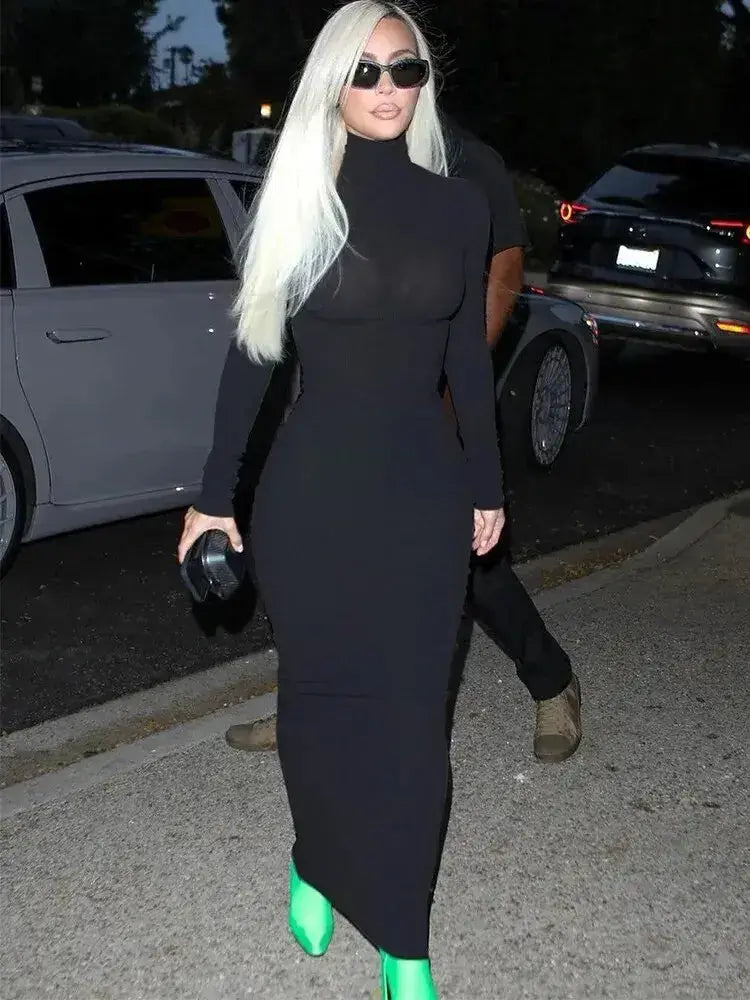 Woman wearing a black casual long sleeve O-neck sheath dress with green shoes walking on a street at night.