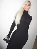Woman wearing a black casual long sleeve O-neck sheath dress with a fitted silhouette and holding a black clutch