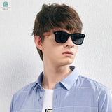 Young man wearing men's vintage natural wooden sunglasses with polarized black lenses and brown wooden frames