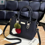 Black vintage PU leather handbag with plush tricolor tassel and detachable shoulder strap on wooden table
